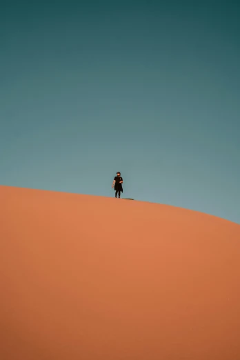 the man is standing on top of the sand dune
