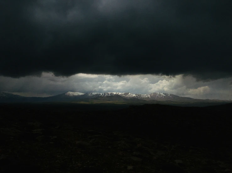 clouds over a mountain range with snow in the mountains