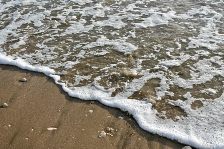 water laping up on the sandy shore with rocks