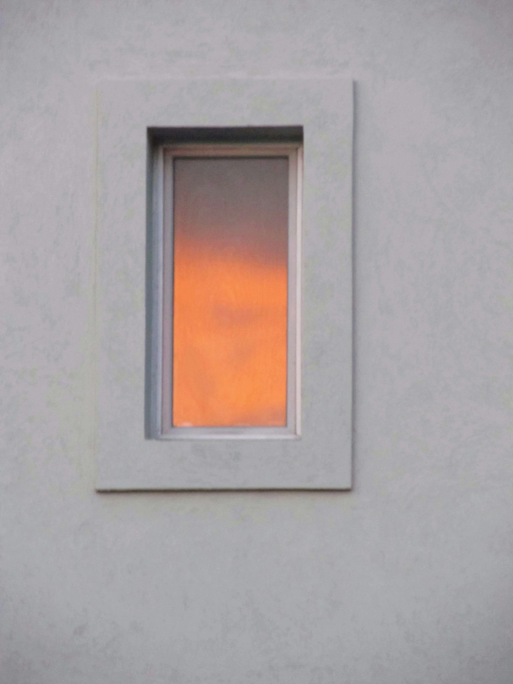 a red window on the side of a grey building