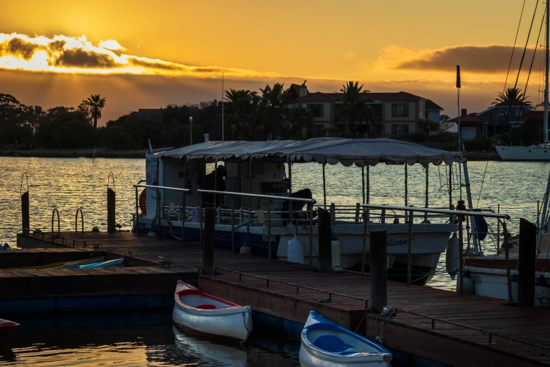 three boats docked on a lake with the sun setting in the background