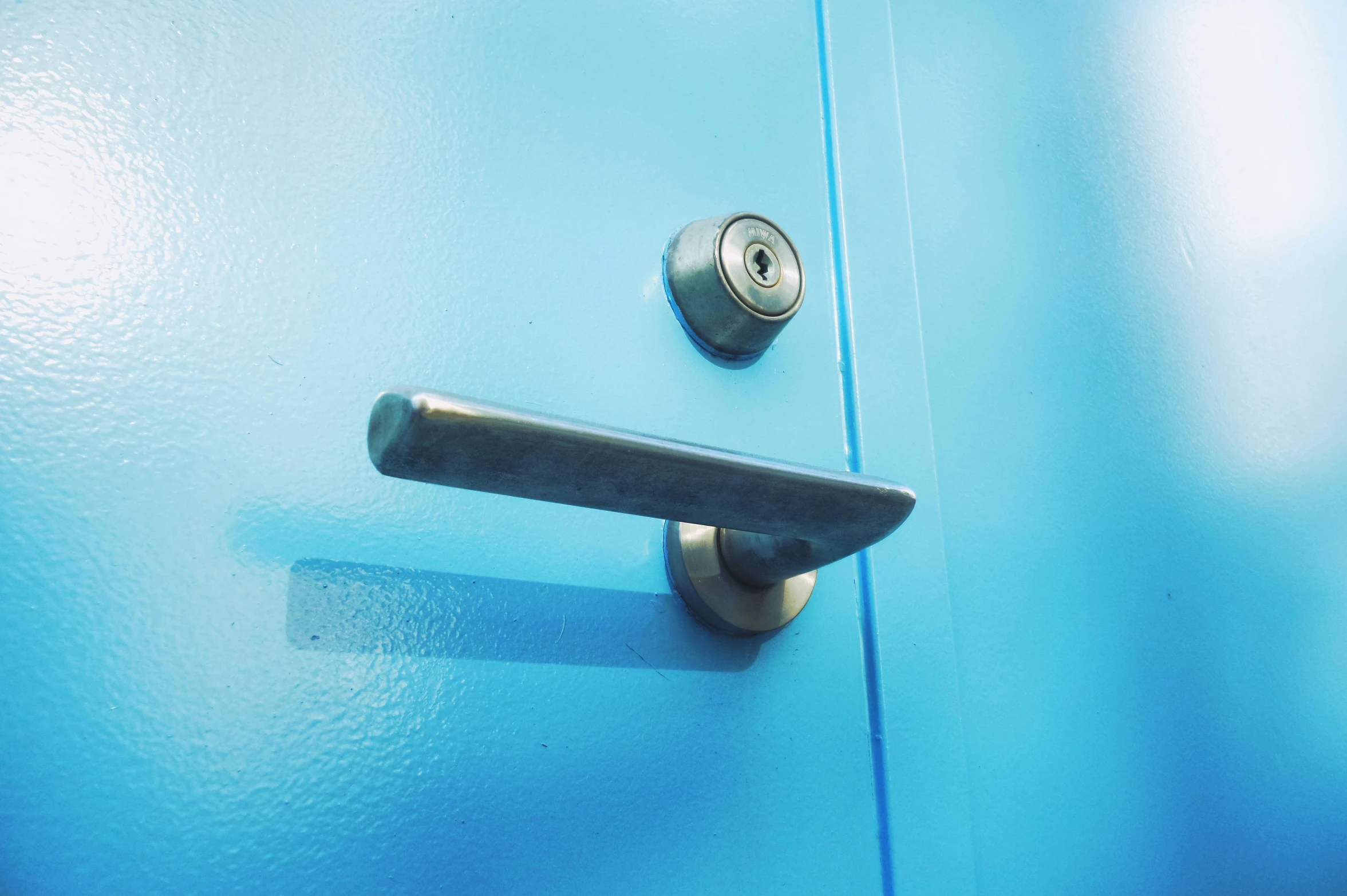 a door handle that is on a light blue metal cabinet