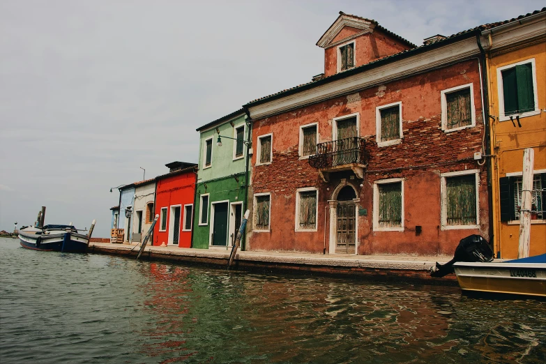 a canal lined with boats next to tall buildings