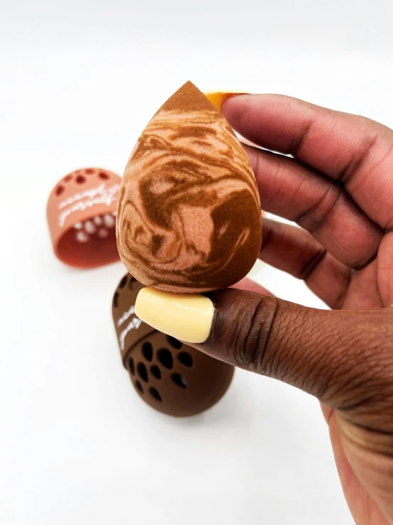 hand holding a decorated doll with a chocolate surface