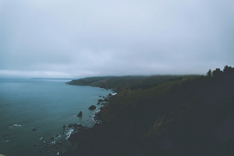 the view from a hill to a blue ocean and clouds