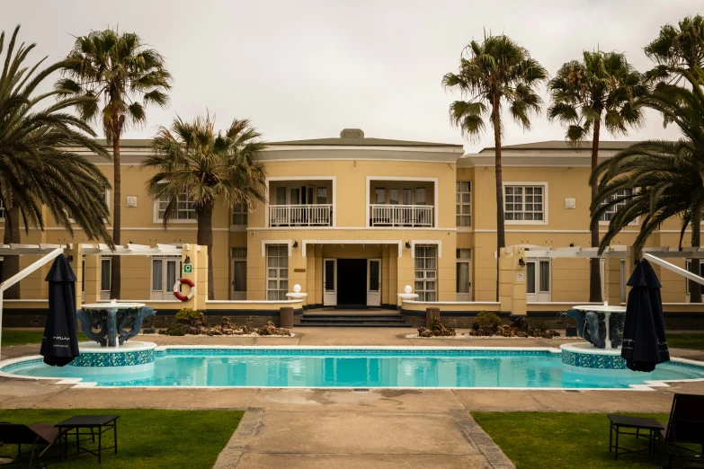 a pool surrounded by lawn chairs with umbrellas