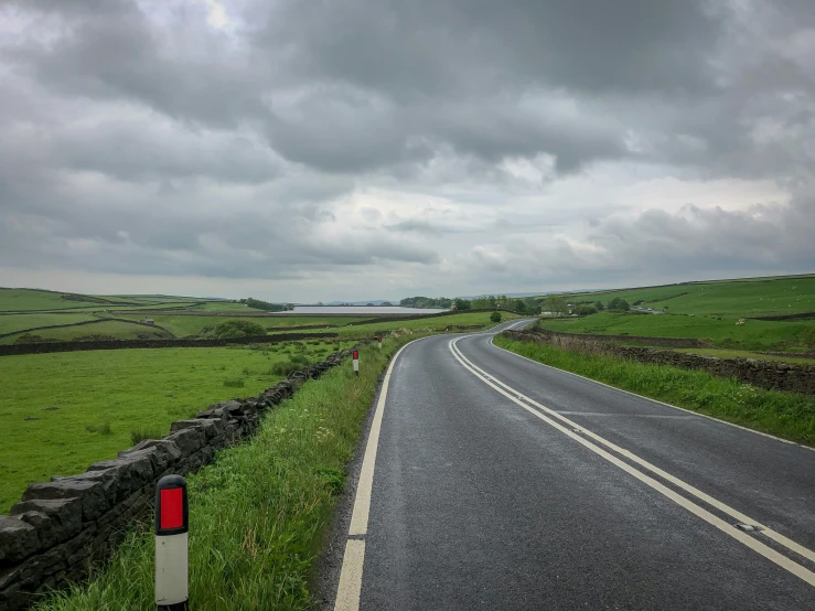 a long road with grass and some stones on the sides