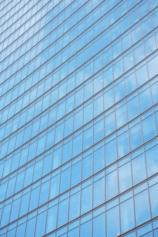 a blue tall building that is reflecting the sky