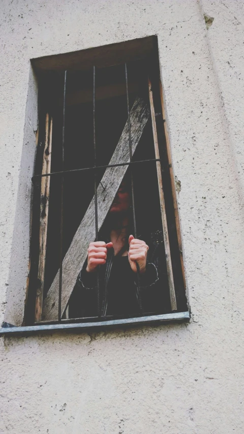 a person behind bars looking out of a window