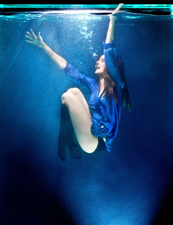 a young woman is floating underwater with her arms extended