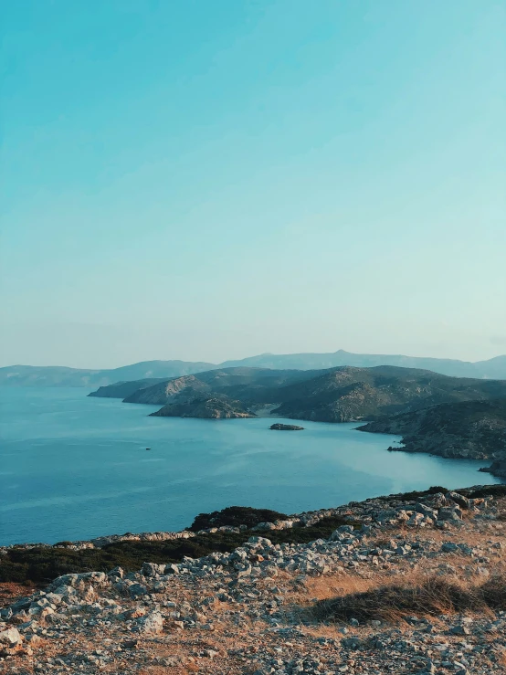 a person standing on top of a hill with mountains and water in the background