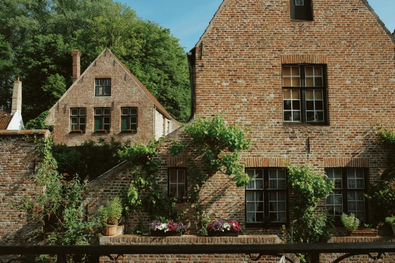 a very large brick building with windows surrounded by lush green trees