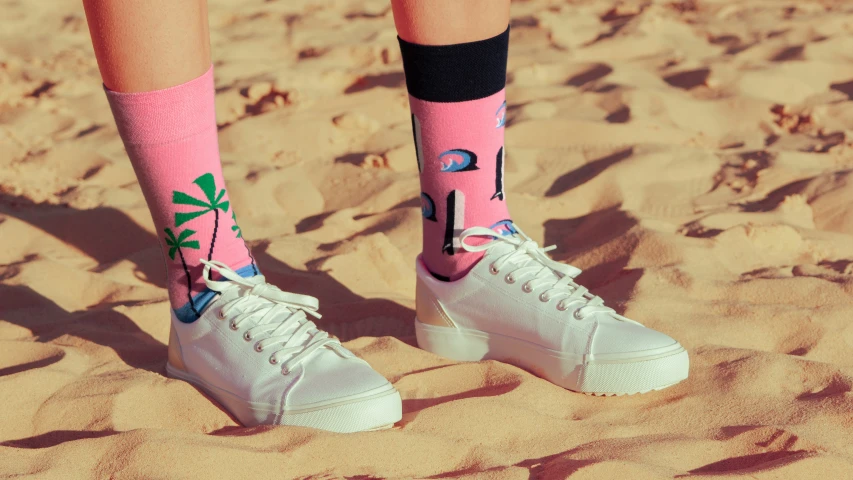a person wearing pink sock covers standing on the beach