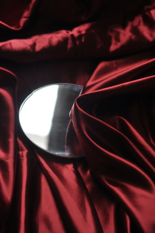 a circular mirror in red silk covering the floor