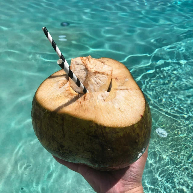 someone holding a half eaten coconut in the water