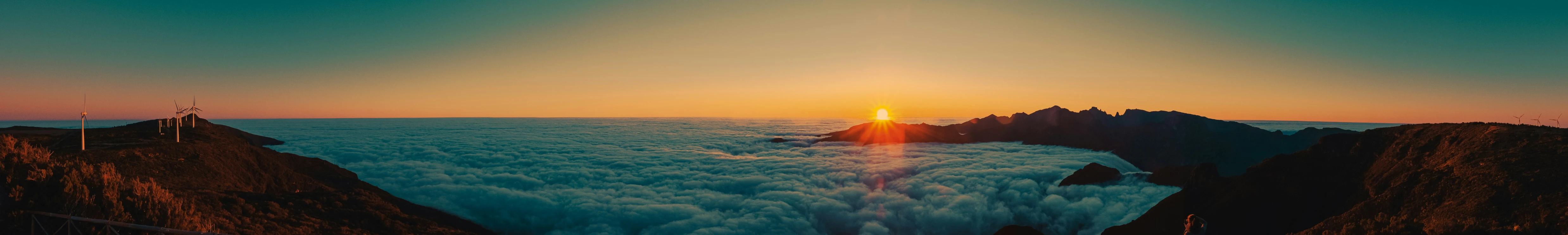 sun rising over fog covered mountain tops as seen from above