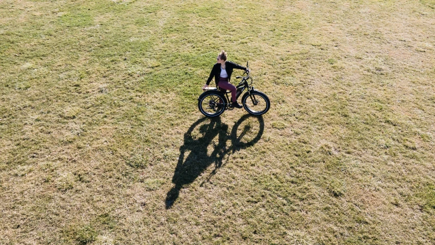 a person riding a bicycle on top of a green field