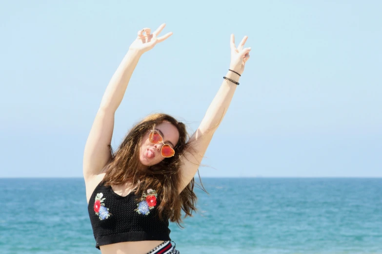 a young woman posing in front of the ocean and wearing sunglasses