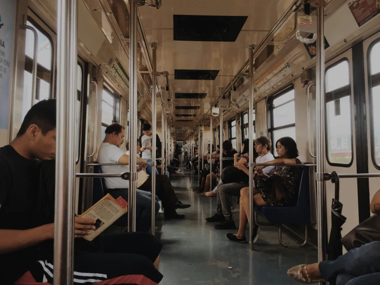 many people sitting on a train looking at their cell phones