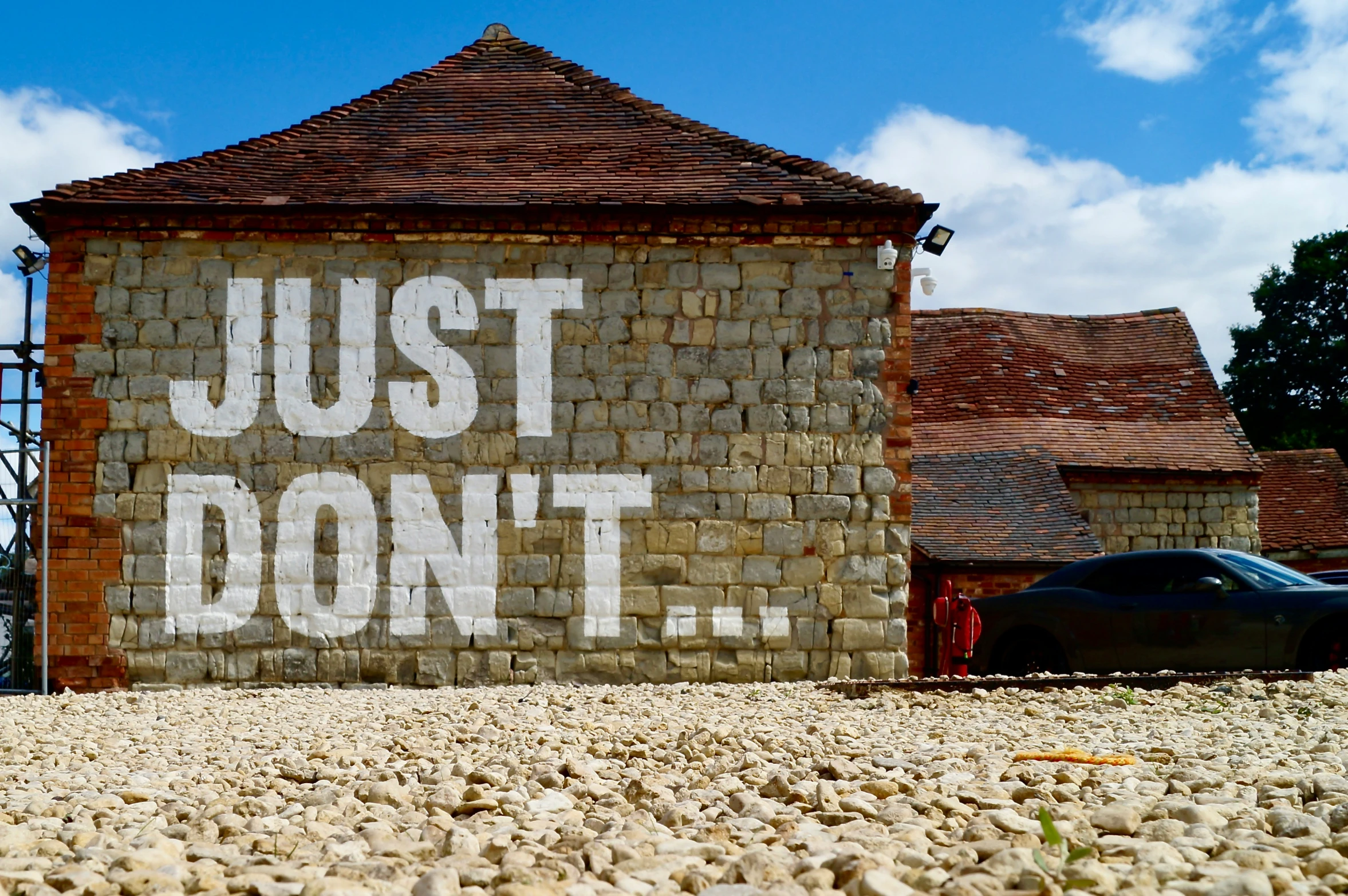 two cars parked outside of a brick building that says just don't