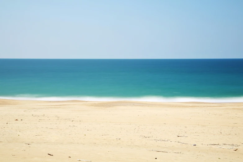 a sandy beach with blue water next to it