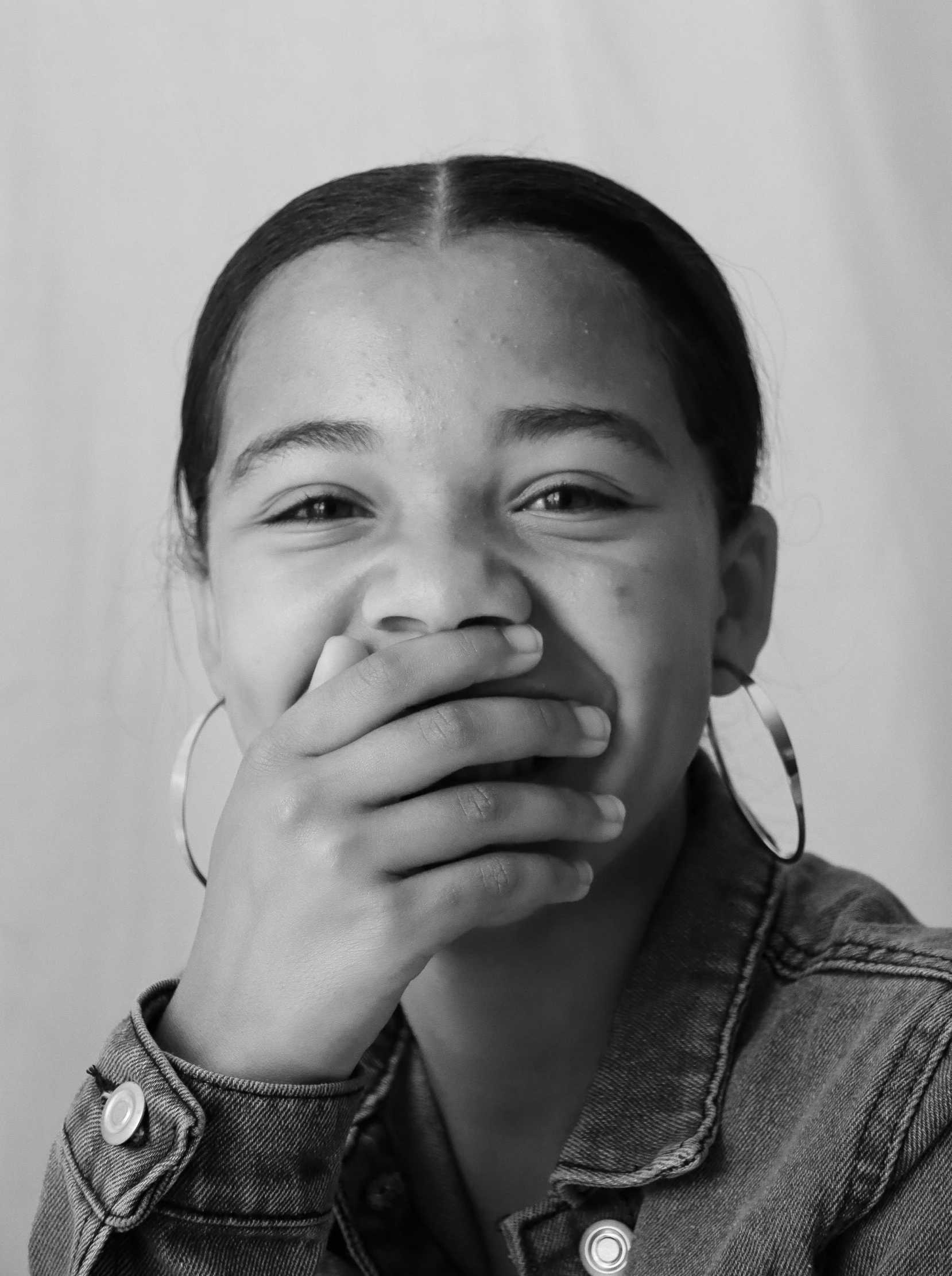 a woman in black and white poses with her hands behind her face