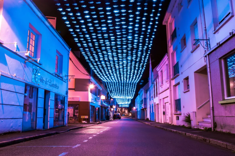a street lined with blue lit buildings on either side
