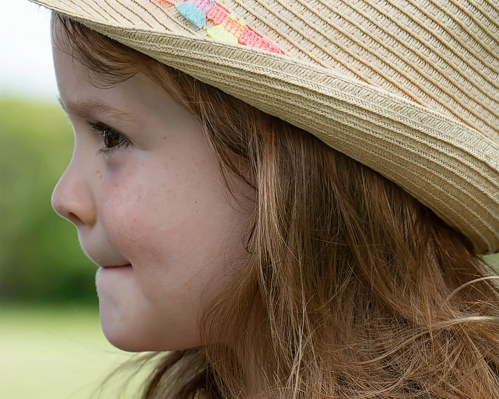 a little girl in a straw hat looking into the distance