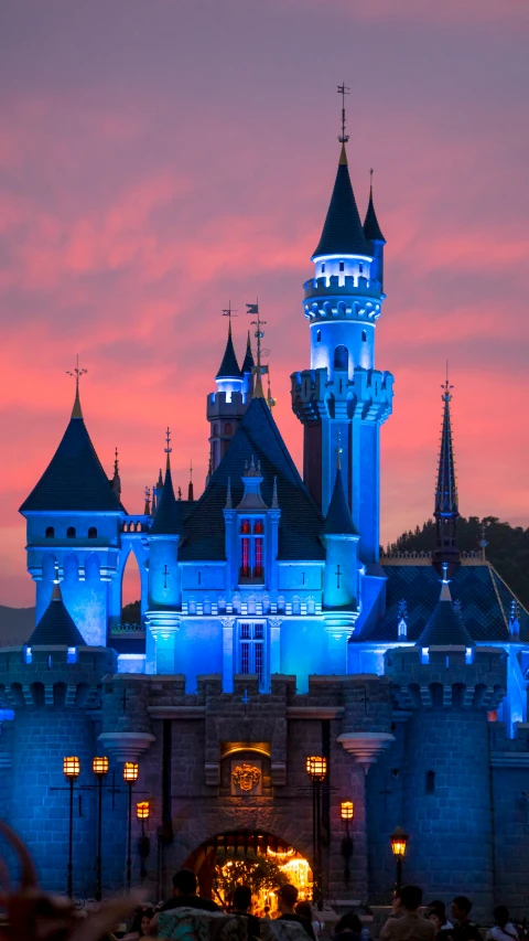 a castle with a few towers lit up with blue lights