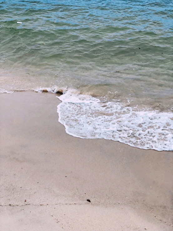 a beach scene with waves and sand on the shore