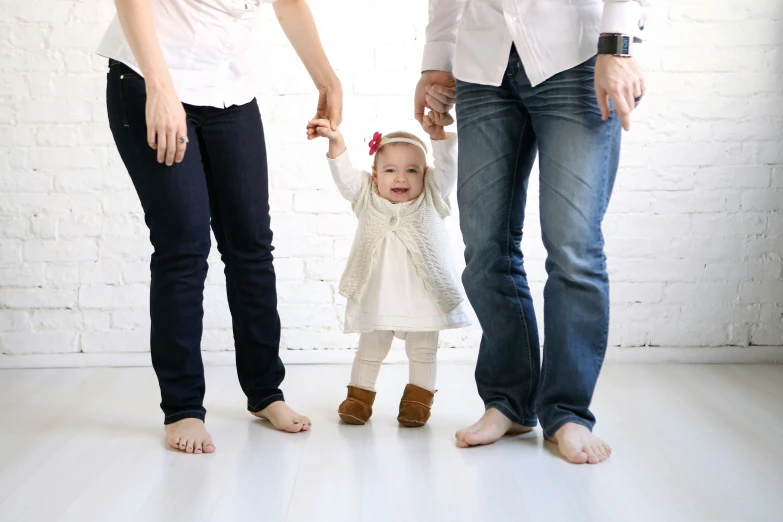 an adorable little girl standing between two adults holding hands