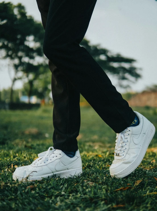 person wearing white sneakers standing on grass