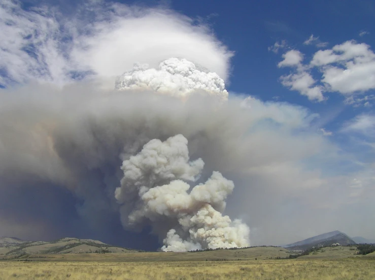 a huge plume of smoke rising from the top of a cloud