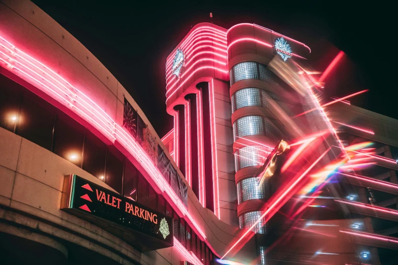 large neon sign with building in background and lights
