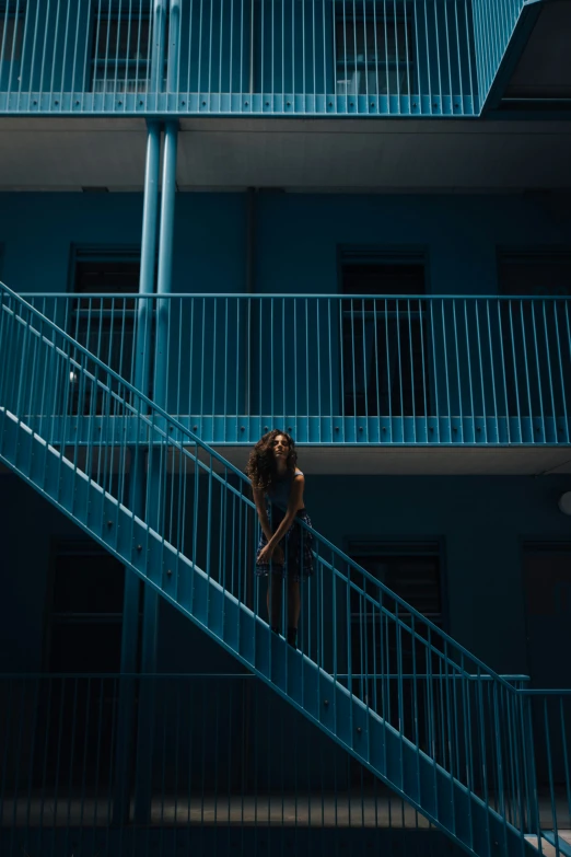 a woman standing on the stair way near a blue building