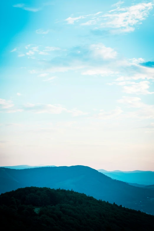 blue sky and clouds above some mountains at dusk