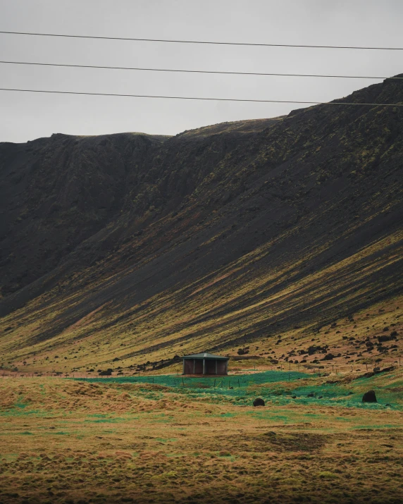 a lone cabin sitting on a grassy hillside