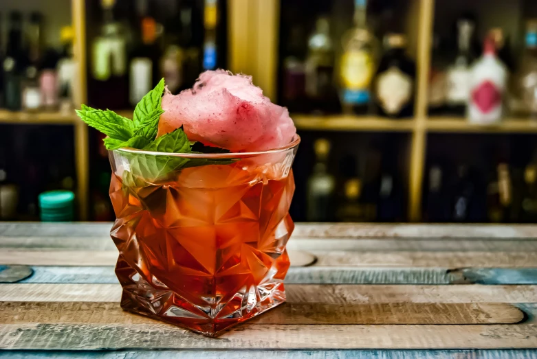 a glass on a wooden table with a pink drink in it