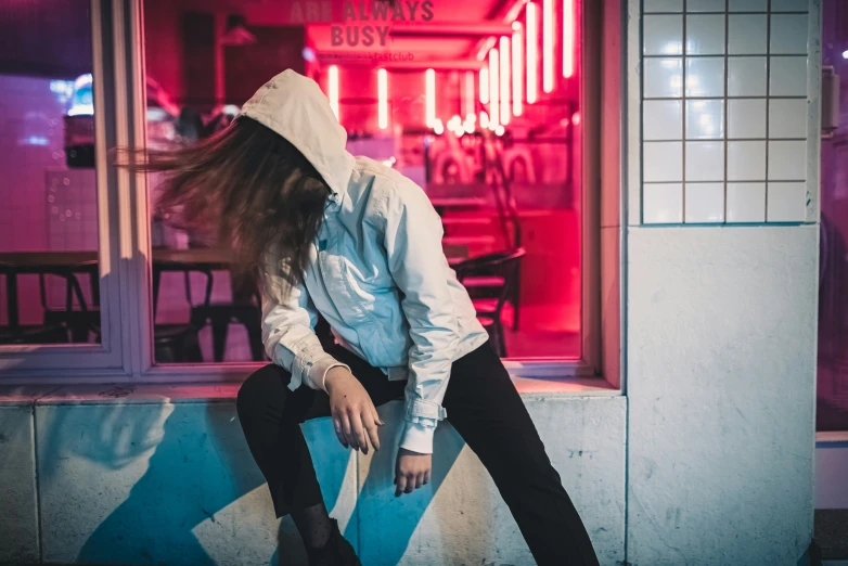 a person sits on a ledge in front of a neon shop