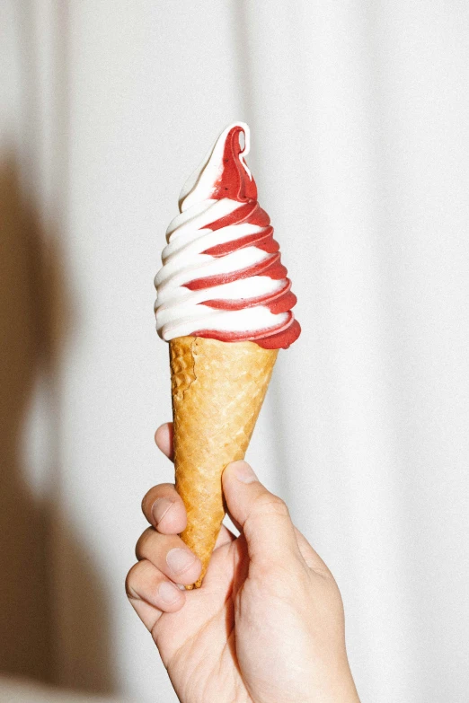 a hand holding an ice cream cone filled with icing