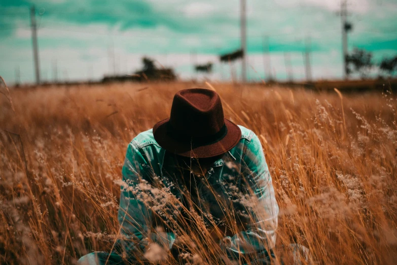 a girl sits in the tall grass outside