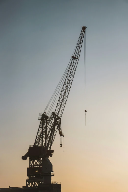 the tower crane is in the sunset on a large building