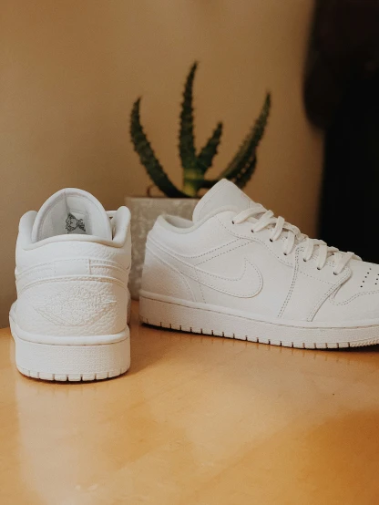 two white sneakers with one white on a table