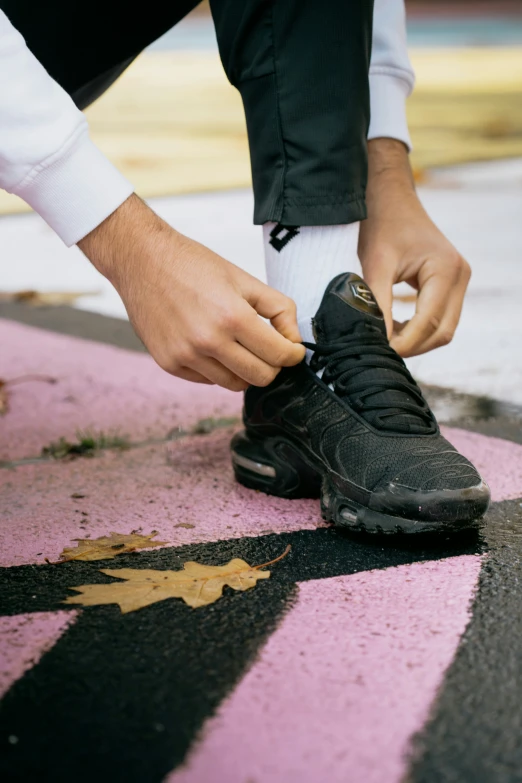 a man tying shoes with one hand while standing on the ground