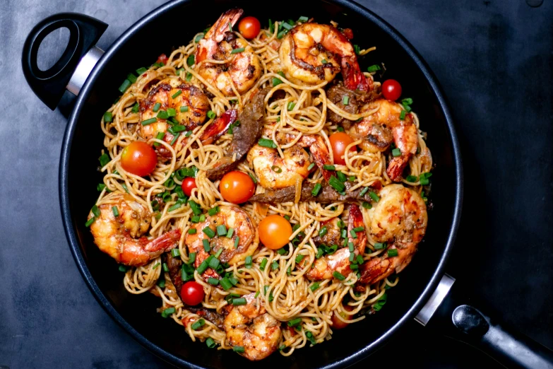 a pan of shrimp and pasta with tomatoes