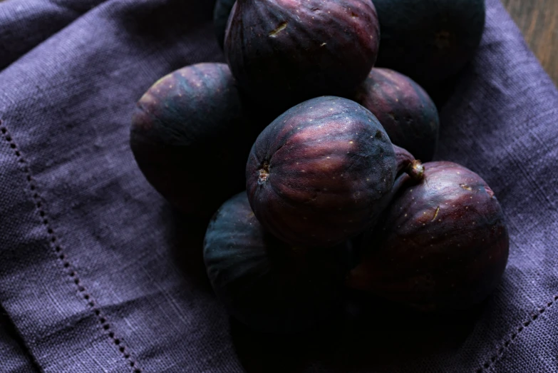 a pile of fresh plums on a blue napkin