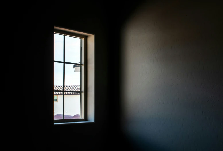 a window in a dark wall with no sunlight in it