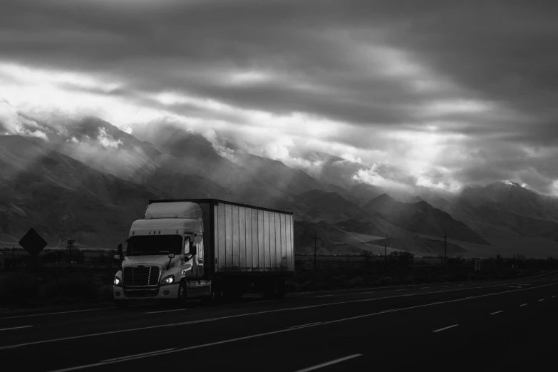 a black and white image of a truck traveling down the highway