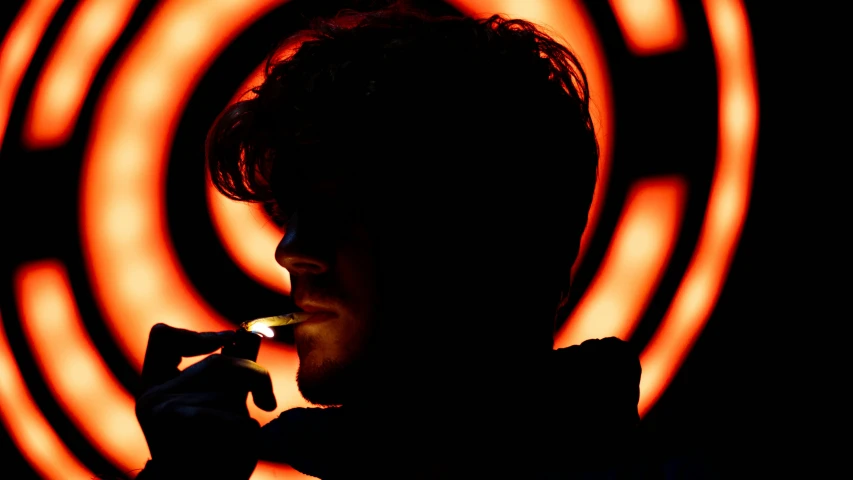 the silhouette of a man smoking an electronic cigarette