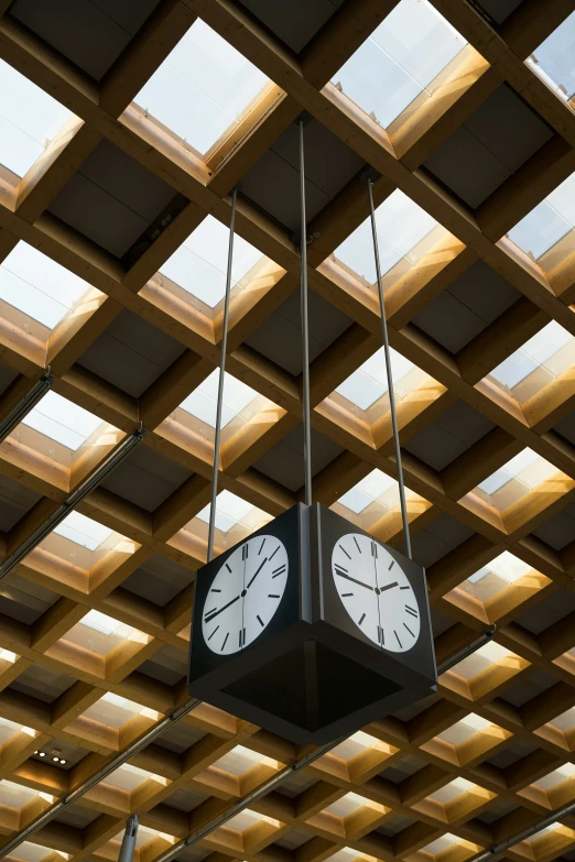 a black and white clock is suspended from a pole